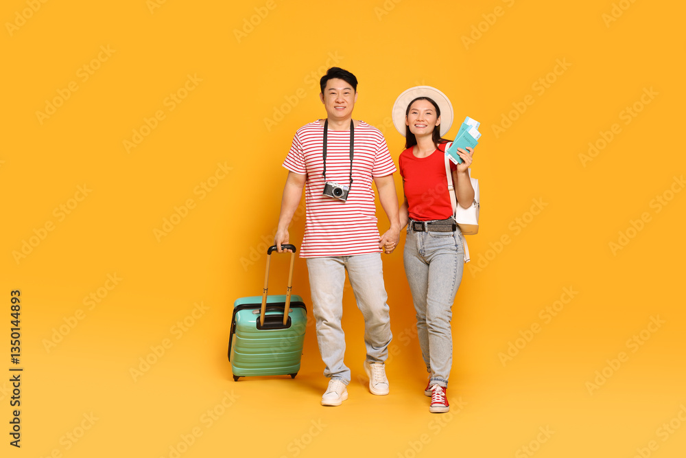Happy travellers with passports and suitcase on yellow background Happy travellers with passports and suitcase on yellow background