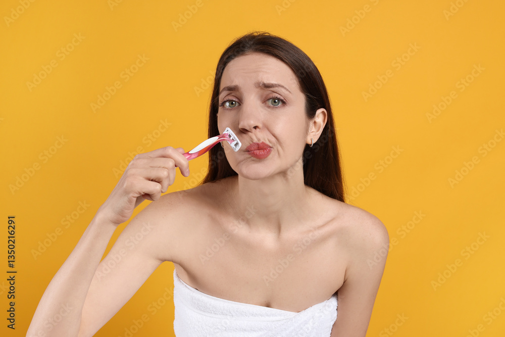 Beautiful woman shaving her mustache with razor on orange background Beautiful woman shaving her mustache with razor on orange background