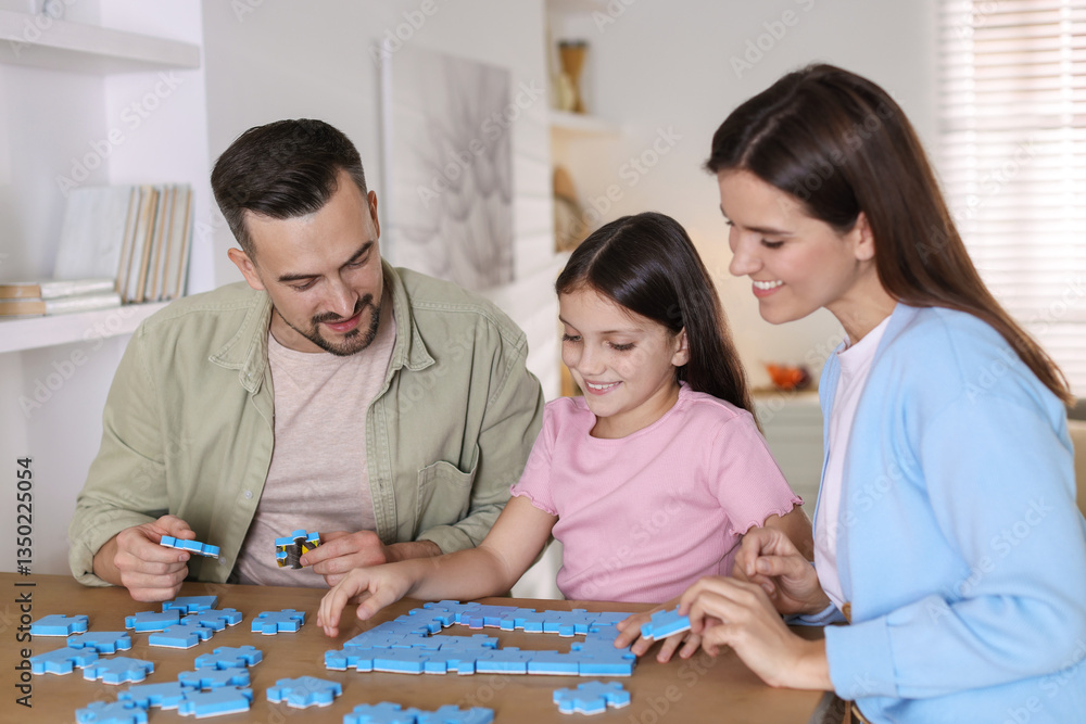 Fototapeta premium Happy parents and their daughter solving puzzle together at wooden table indoors
