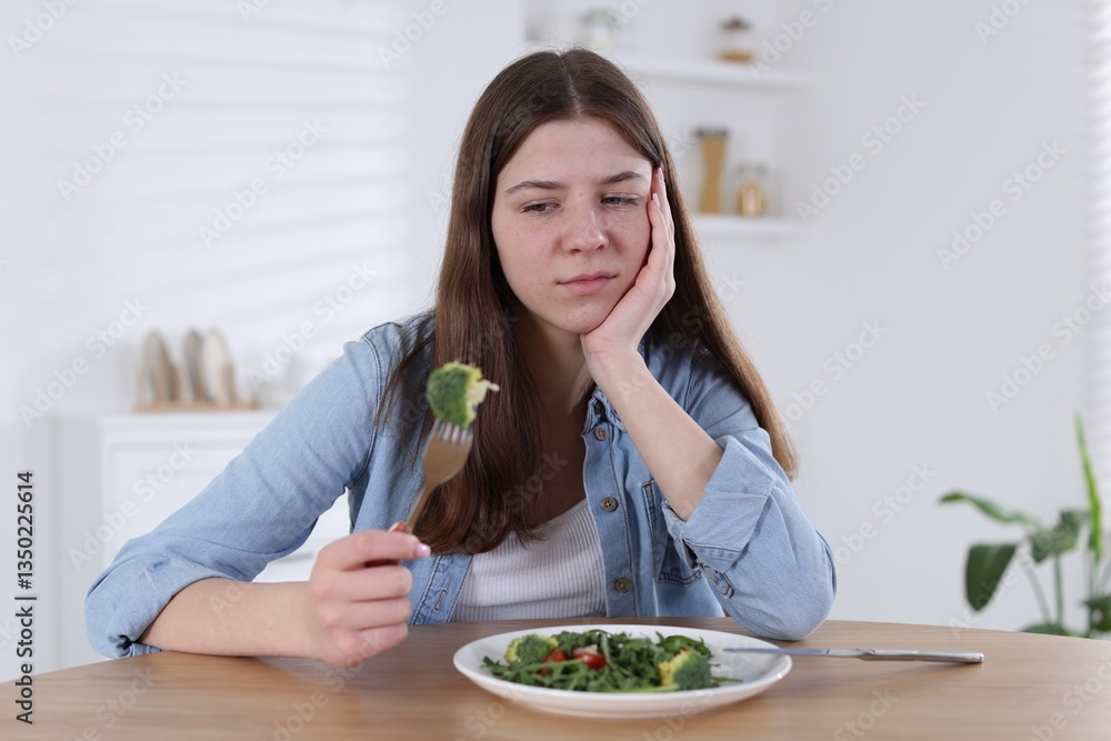 Sad teen girl holding fork with broccoli at home. Eating disorder Sad teen girl holding fork with broccoli at home. Eating disorder