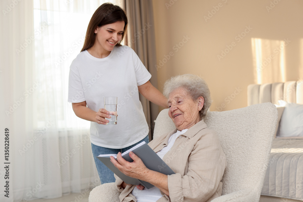 Obraz premium Granddaughter giving glass of water to her grandmother at home. Elderly care