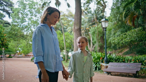 Happy mother going daughter lush green garden alley at family weekend closeup