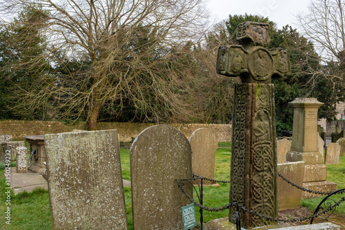 Eham, Chesterfield, United Kingdom - 21 Mar 2025 - A cemetery with a cross and several gravestones. The cross is in the middle of the cemetery and is surrounded by a chain link fence. The cemetery is 