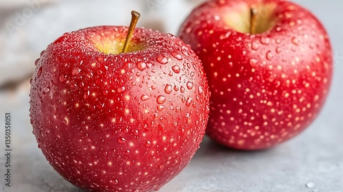 Two fresh red apples with water droplets.