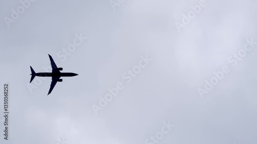 Lower view of an airplane flying above the camera in cloudy sky. Aircraft overhead bottom view.