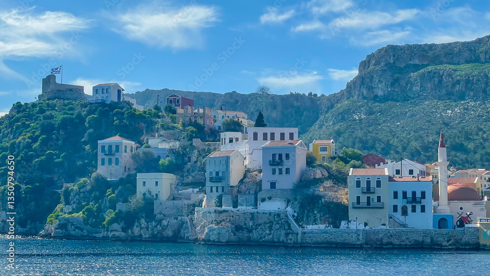 Fototapeta premium Traditional Houses On The Hillside Of Kastellorizo Island, Greece, Overlooking The Blue Sea, With A Greek Flag Flying Above, Scenic Summer Destination, Cultural Heritage, Ideal For Travel And Tourism.