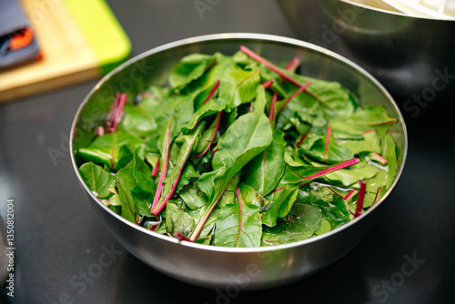 Canvas-taulu Fresh leafy greens soaking in stainless steel bowl