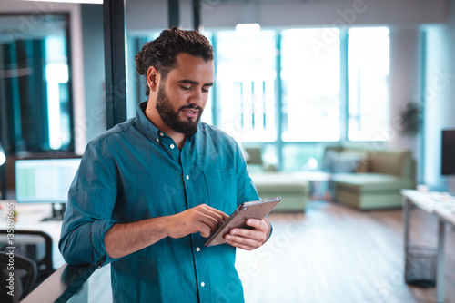Businessman using tablet in modern office, focusing on digital tasks, copy space