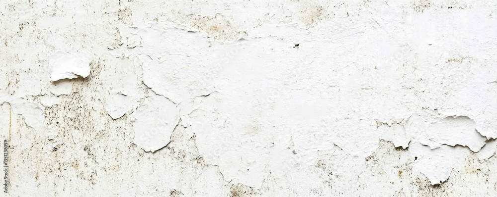 Fototapeta premium A weathered white wall showcases layers of peeling paint, revealing hints of faded colors beneath. The texture adds character, creating a rustic, vintage ambiance in the space.