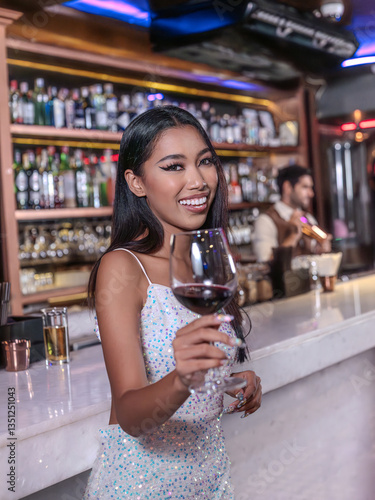 Obraz na płótnie A glamorous woman in a sparkling sequin dress holding a glass of red wine at an elegant bar. She smiles confidently, radiating sophistication and charm. The luxurious bar setting w salonie