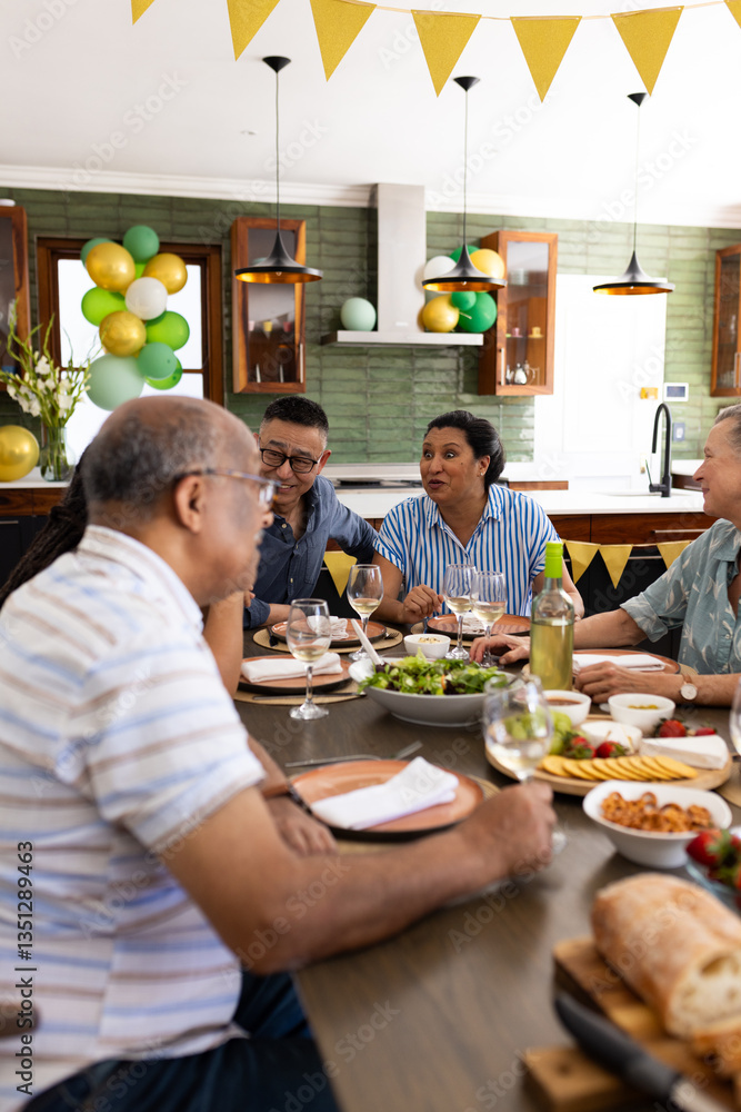 Group of diverse senior friends enjoying lunch and conversation at home, celebrating together Group of diverse senior friends enjoying lunch and conversation at home, celebrating together