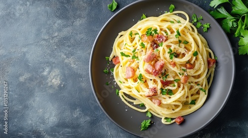 Delicious pasta with bacon and herbs served on dark plate