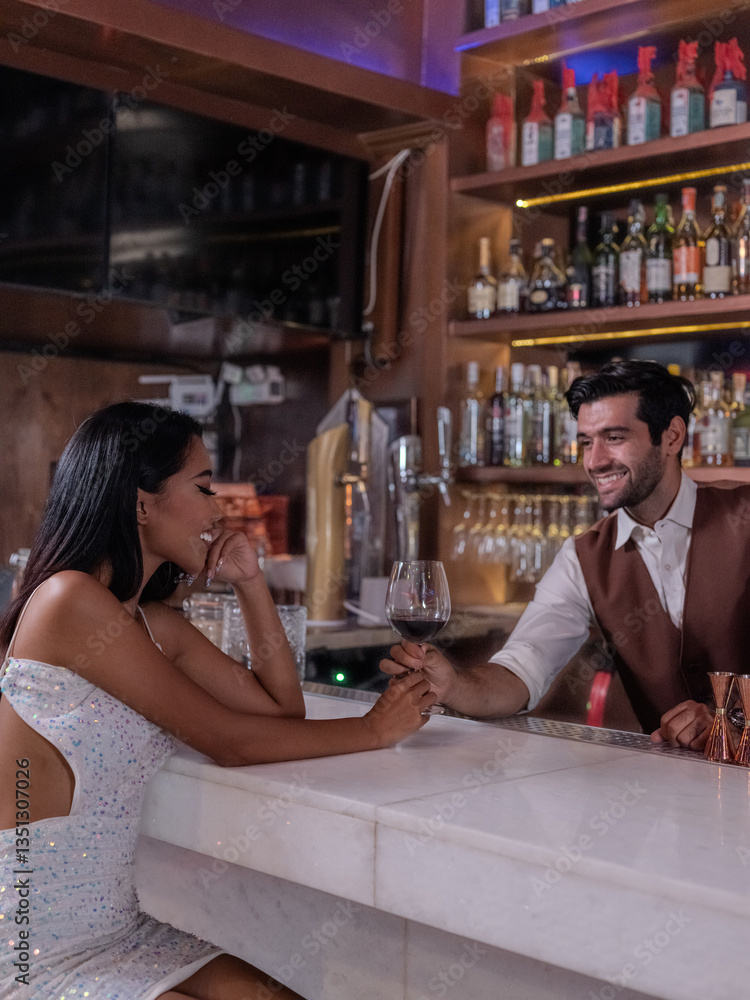 Bartender giving glass of wine to woman customer at bar counter .