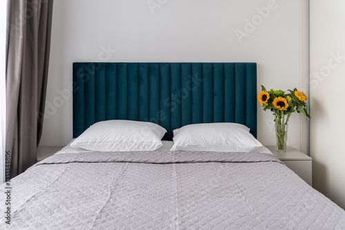 Wallpaper Mural simple interior of modern bedroom. double bed with soft blue headboard, white linens, and gray bedspread. vase with beautiful yellow sunflowers on bedside table. Photograph of bedroom Torontodigital.ca