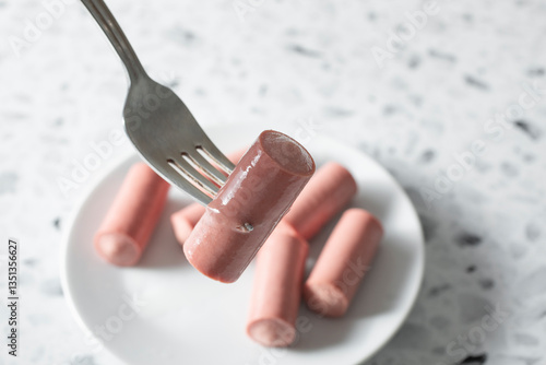 A closeup view of a fork picking up a Vienna sausage.