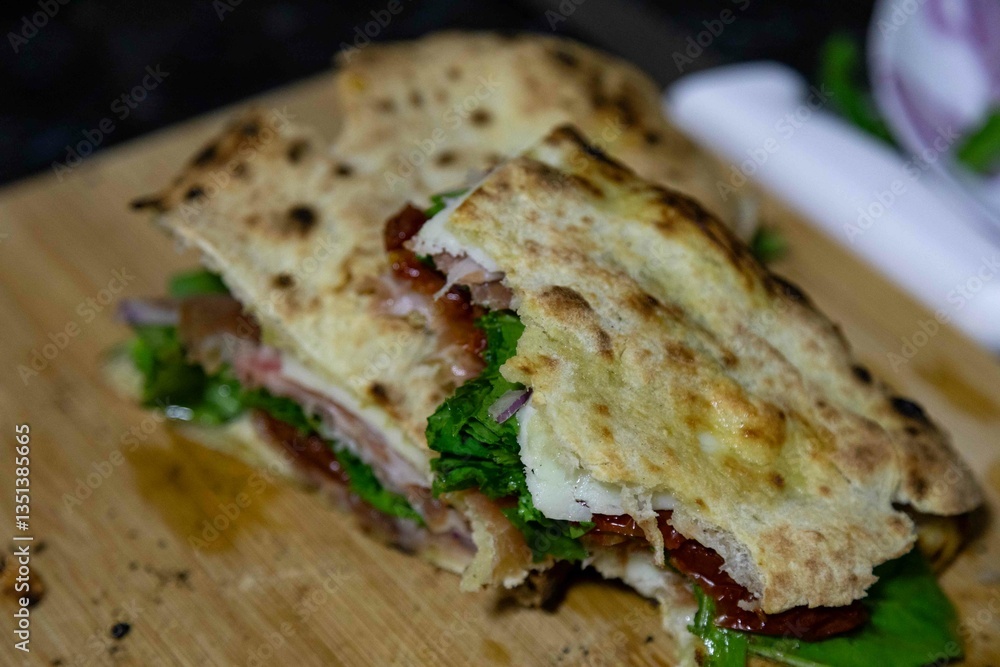 Traditional Italian Neapolitan panuozzo prepared with artisanal pizza dough, arugula and sun-dried tomatoes Traditional Italian Neapolitan panuozzo prepared with artisanal pizza dough, arugula and sun-dried tomatoes