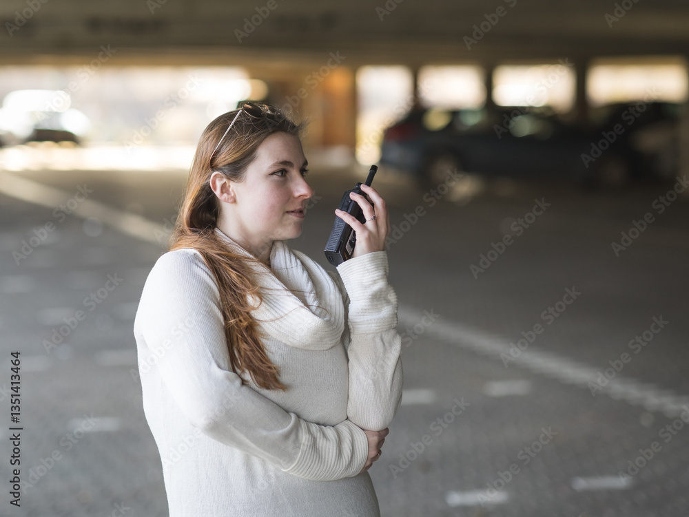 Woman with sunglasses using a walkie talkie in a car parking Woman with sunglasses using a walkie talkie in a car parking