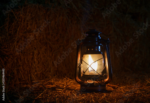antique kerosene lamp with lights on a haystack in a barn at night