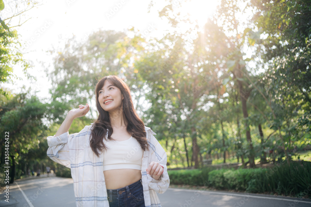 Asian woman enjoying summer outdoors, breathing fresh air in park with sunlight filtering through trees, feeling relaxed and happy Asian woman enjoying summer outdoors, breathing fresh air in park with sunlight filtering through trees, feeling relaxed and happy