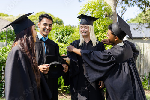 Diverse graduates in caps and gowns celebrating together in garden, smiling and joyful