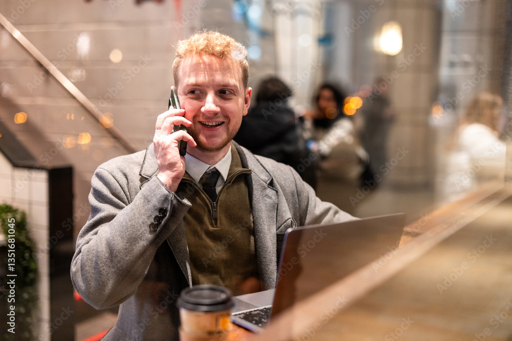 Businessman talking on phone and working on laptop in cafe