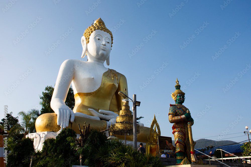 Fototapeta premium Big golden buddha image statue of Wat Phra That Doi Kham Temple for thai people and foreign travelers travel visit and respect praying at Mae Hia city on November 10, 2020 in Chiang Mai, Thailand
