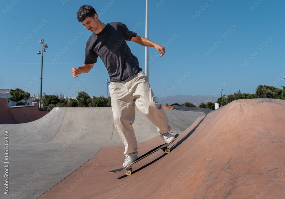 Obraz premium young skater wearing black tshirt skating in a skate park in a sunny day