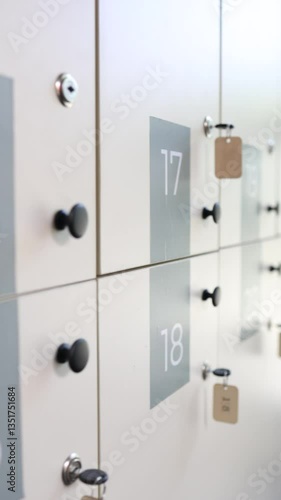 Secure lockers with numbered panels and keys hanging on white doors in a public facility in vertical video