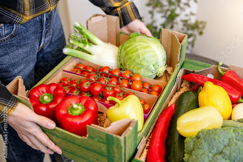 Fototapeta Naklejka Na Ścianę i Meble -  Farm grown fruits and vegetables in cardboard box. Woman unpacking her online order of organic and healthy vegetables.	