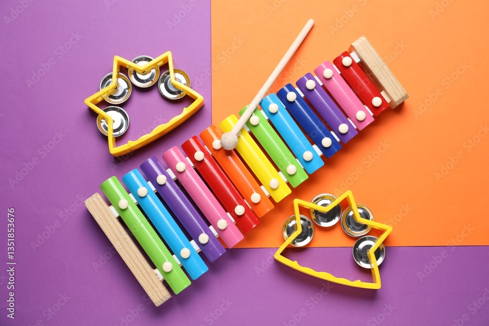 Fototapeta premium Toy xylophone with mallet and tambourines on color background, flat lay
