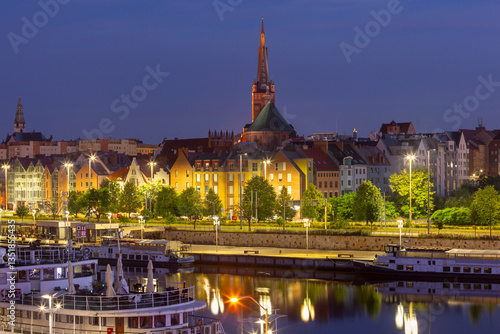 Obraz na płótnie Oder River waterfront in Szczecin Poland with illuminated buildings and docked boats before sunrise w salonie