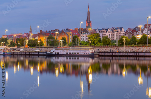 Obraz na płótnie Oder River waterfront in Szczecin Poland with illuminated buildings and docked boats before sunrise w salonie