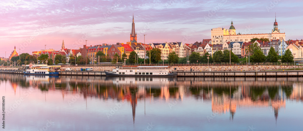 Oder River waterfront in Szczecin Poland with illuminated buildings and docked boats before sunrise
