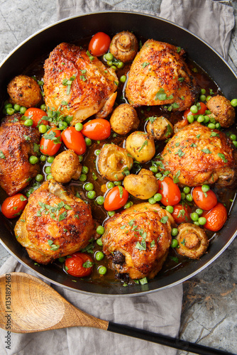 Obraz na płótnie Chicken thighs baked with mushrooms and vegetables close-up in a frying pan on the table. Vertical top view from above w salonie