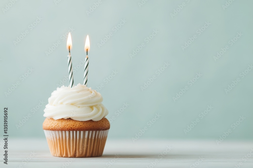 cupcake with two burning candles for second birthday celebration on pastel background