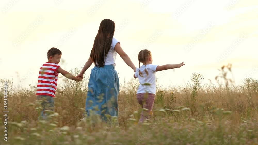 Loving mother with little children plays plane running across field grass at sunset light. Children play with happy mother at country nature. Mother and children on summer vacation at countryside Loving mother with little children plays plane running across field grass at sunset light. Children play with happy mother at country nature. Mother and children on summer vacation at countryside