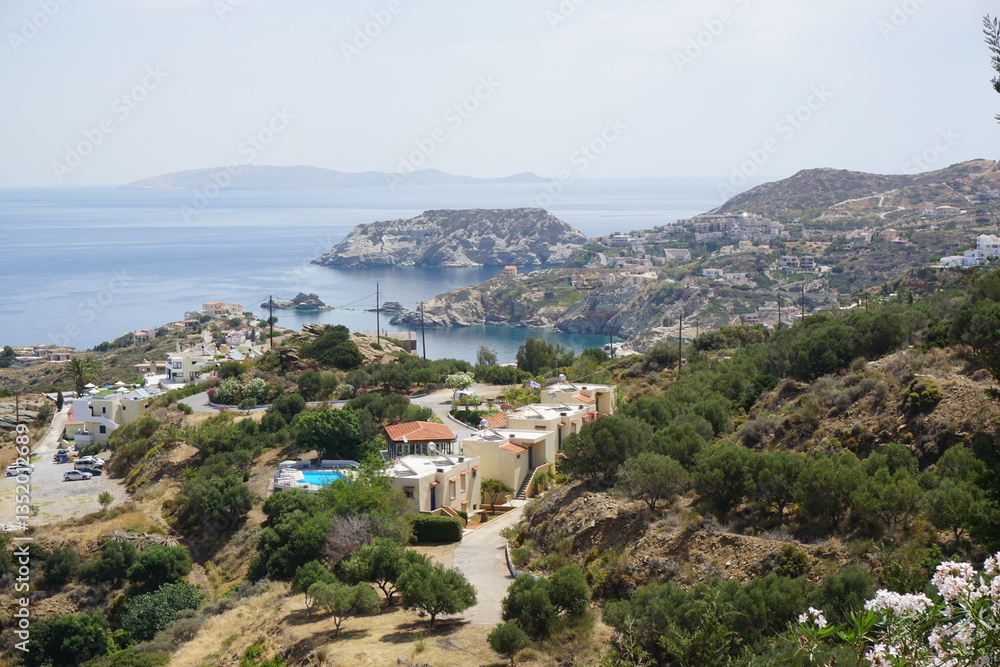 Fototapeta premium Panoramic view of Agia Pelagia in Crete, Greece from above with the blue sea and the clear blue sky in the background - Holiday homes, villas and hotels with swimming pools amidst beautiful vegetation