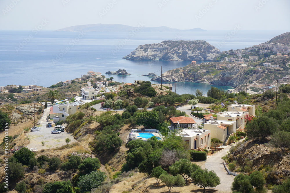 Fototapeta premium Panoramic view of Agia Pelagia in Crete, Greece from above with the blue sea and the clear blue sky in the background - Holiday homes, villas and hotels with swimming pools amidst beautiful vegetation