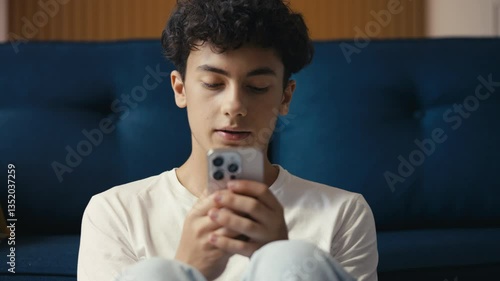 Sad teen boy reading a bad news text on his phone, struggling with cyberbullying