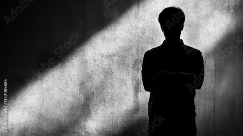 Silhouette man, arms crossed, in shadowed room