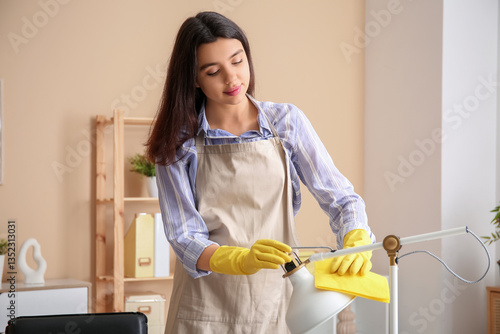Young woman cleaning lamp w...