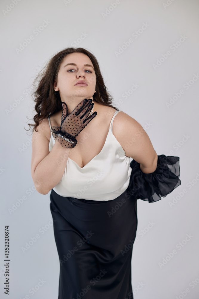 Fototapeta premium Elegant woman confidently posing in sophisticated black-and-white attire with a delicate sheer glove, perfect imagery for fashion campaigns, beauty editorials, or expressive portraiture.