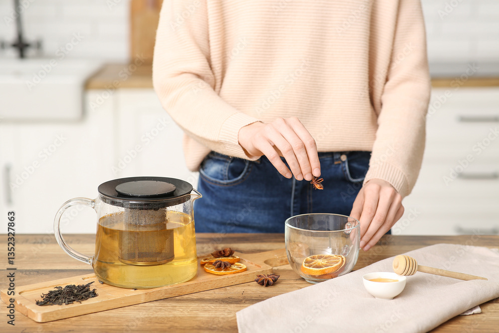 Young woman adding star anise in tea cup in kitchen Young woman adding star anise in tea cup in kitchen