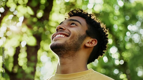 A joyful man stands beneath a lush tree canopy, surrounded by a dreamy bokeh backdrop.