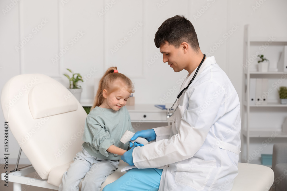 Obraz premium Male pediatrician measuring temperature of little girl with infrared thermometer in clinic