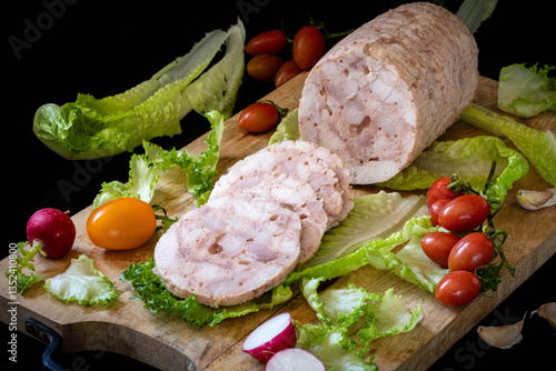 Chopped ham. Homemade sausage, decorated with lettuce leaves and vegetables on a wooden board.
