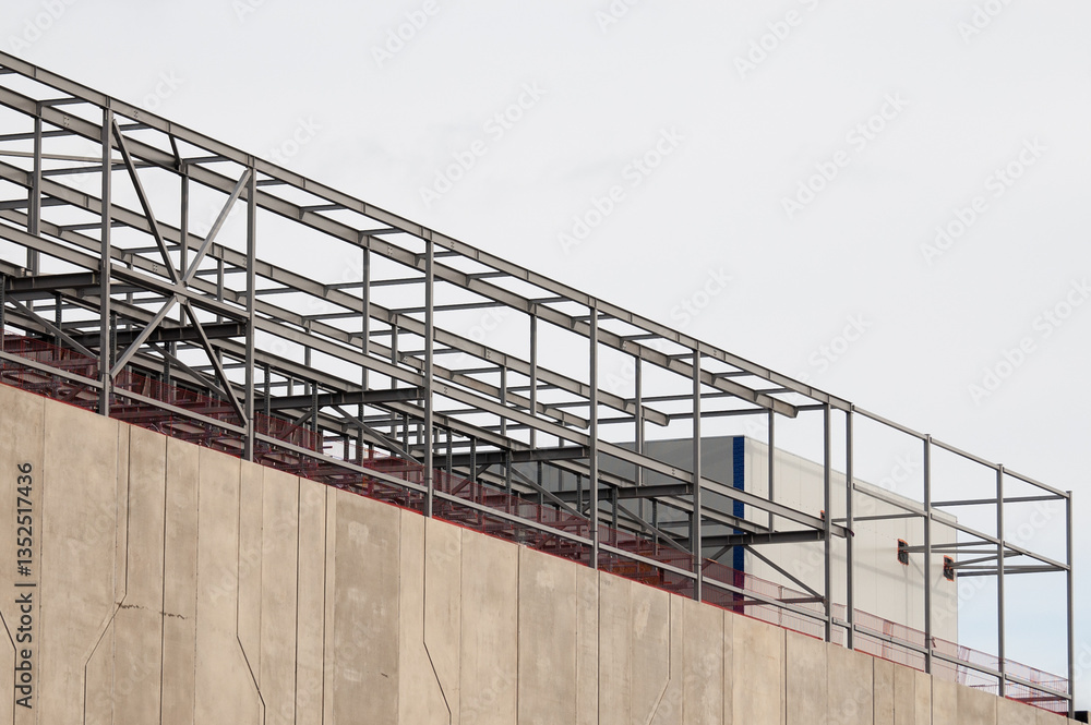 Fototapeta premium concrete building and metal beam frame during construction against grey sky