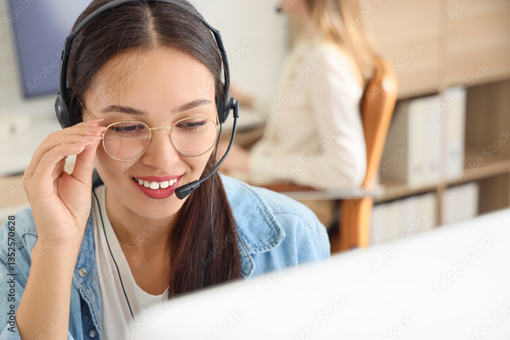 Female Asian technical support agent with headset working in office, closeup Female Asian technical support agent with headset working in office, closeup