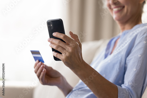 Close up cropped shot smiling aged female holding smartphone credit bank card in hands. Safe online banking secure internet payments easy ordering at web store prepaid goods services ecommerce concept