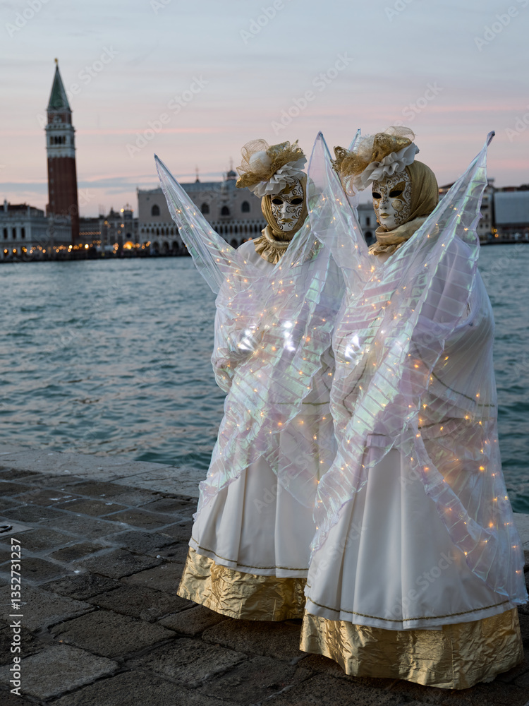 Obraz premium Venice, Italy - People dressed in carnival masks are photographed by tourists in the scenery of the ancient Venetian palaces